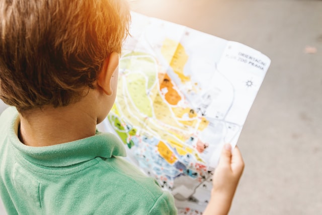 Boy standing while reading map.