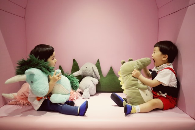 Boy and girl telling stories playing with soft toys