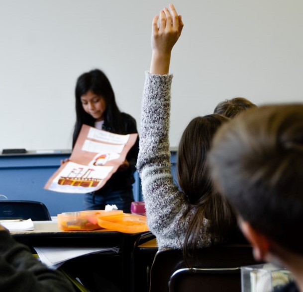 Girl raises hand in class.