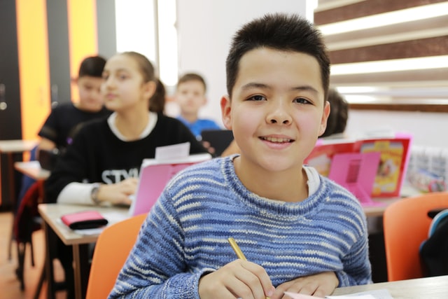 Boy writing in school classroom.