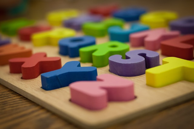 Colourful alphabet blocks sitting in a wooden board. RST and XYZ are visible in two rows.