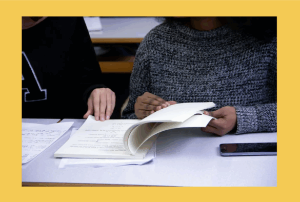Two people looking through a textbook.